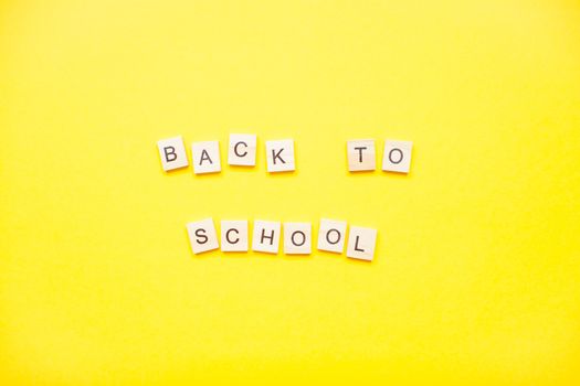 Words from wooden blocks "back to school" on bright yellow background