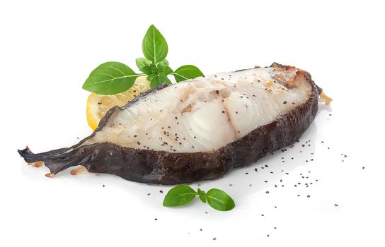 Isolated baked catfish steak with basil and lemon