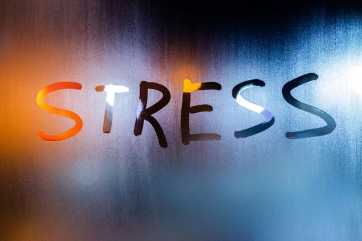 the word stress handwritten on night wet window glass in teal-orange tones with selective focus.