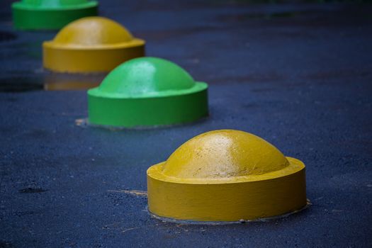 colorful concrete road parking prevention hemisphere bollards close-up with selective focus and blur.