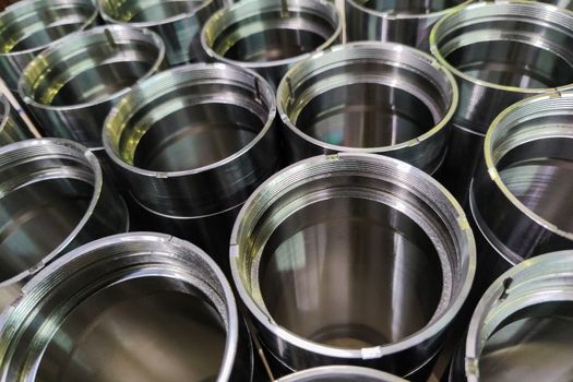 A close-up shot of shiny steel aerospace cnc turned tubes in a batch with selective focus and background blur.