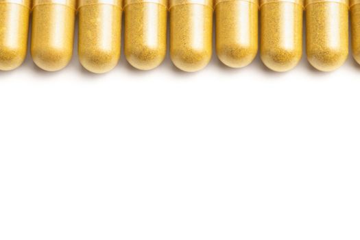 row of orange color organic capsules isolated on white background closeup with selective focus.