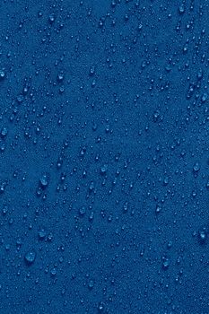 classic blue color waterproof hydrophobic flat cloth closeup with water drops background.