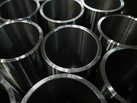 dark industrial background with cnc machined shiny steel pipes - selective focus and lens blur technique