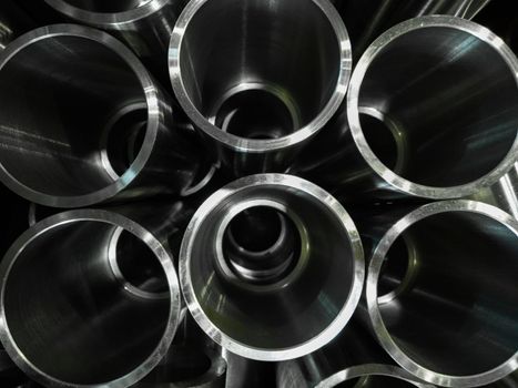 dark industrial background with cnc machined shiny steel pipes - selective focus and lens blur technique