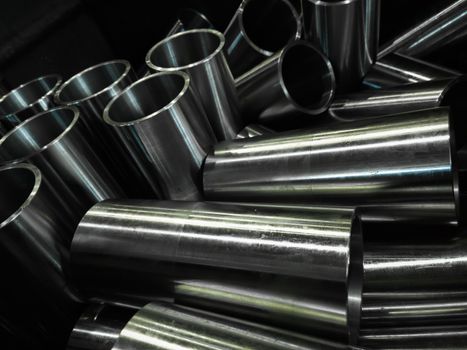 dark industrial background with cnc machined shiny steel pipes - selective focus and lens blur technique