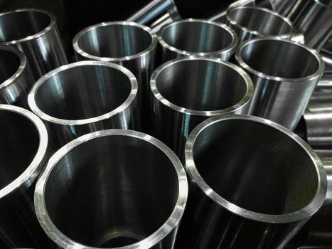 dark industrial background with cnc machined shiny steel pipes - selective focus and lens blur technique