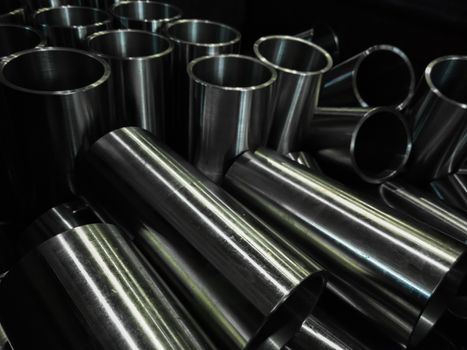 dark industrial background with cnc machined shiny steel pipes - selective focus and lens blur technique