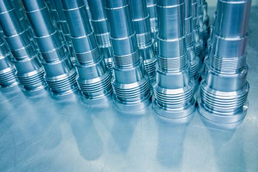 Shiny blue steel parts background, long clean steel threaded rods after fine cnc turning.