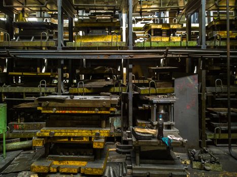 messy stamping shop with large stamps rack inside metalworking factory.