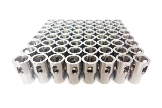 Shiny steel parts after cnc turning, drilling and machining isolated on white background with selective focus.