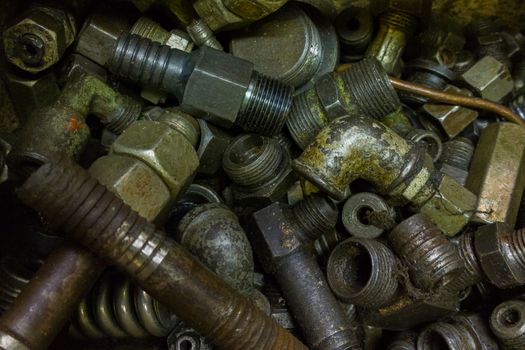 a pile of old dirty hydraulic fittings and tube parts closeup with selective focus.
