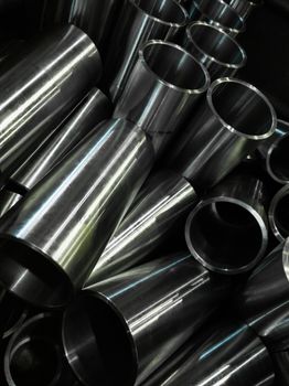 dark industrial background with cnc machined shiny steel pipes - selective focus and lens blur technique