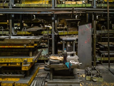 messy stamping shop with large stamps rack inside metalworking factory.