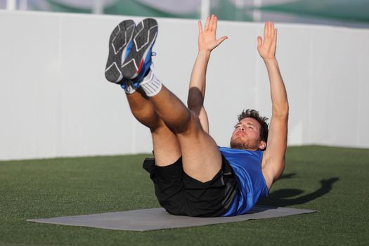 Abs exercise leg lift toe touch sit-up workout man strength training at fitness gym athletic stadium. Athlete working out crunches exercises for stomach muscles and weight loss.