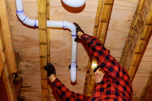 Workers are sewer toilet pipes with PVC joints allows the split the make PVC pipe coming out the other side the buildingceiling beam house.