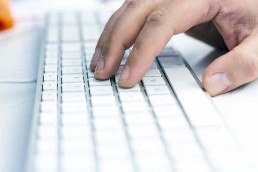 a male hand over the white keyboard of a computer before typing. Work and employment. Technology