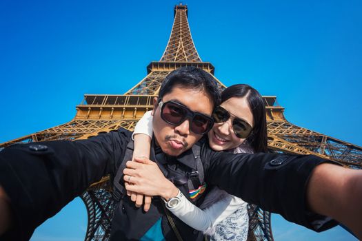 Young Couple Tourists selfie with mobile phone near the Eiffel tower in Paris, France