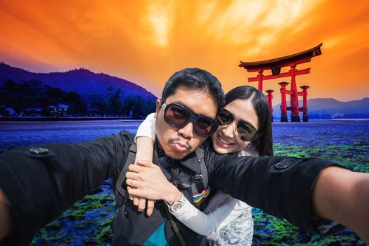 Young Couple Tourists selfie with mobile phone near the Tori gate in hiroshima, Japan