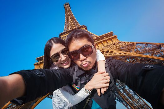 Young Couple Tourists selfie with mobile phone near the Eiffel tower in Paris, France