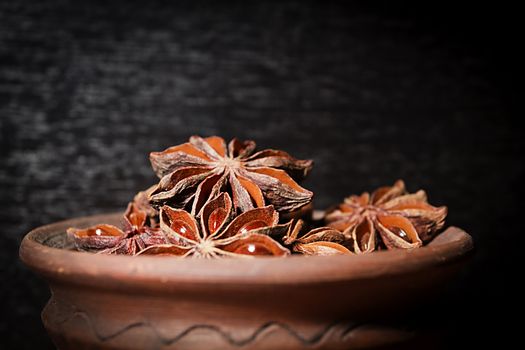 Anis in bowl, dark background, selective focus