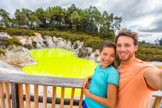 New Zealand tourist attraction couple tourists taking selfie travel destination, Waiotapu. Active geothermal green pond, Rotorua, north island.
