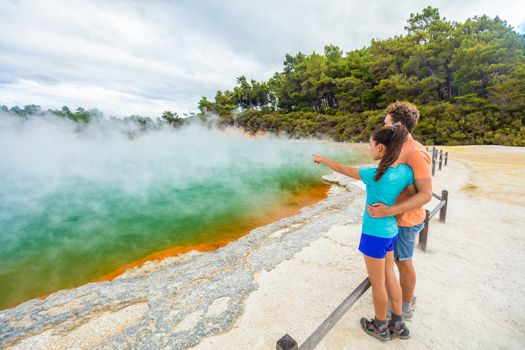 New Zealand travel tourists couple at Champagne pool at Wai-O-Tapu pools Sacred Waters. Tourist attraction in Waiotapu, Rotorua, north island. Active geothermal area, Okataina Volcanic Centre, Taupo.