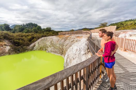 New Zealand travel tourists looking at green pond. Tourist couple enjoying famous attraction on North Island, geothermal pools at Waiotapu, Rotorua.