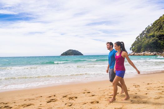 New Zealand beach couple hikers walking the coast track in Abel Tasman National Park. People tramping relaxing in nature outdoors.