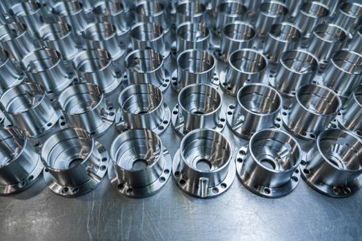 a batch of shiny metal cnc aerospace parts production - close-up with selective focus for industrial background.