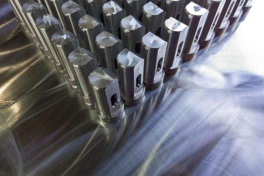 Batch of shiny metal parts after cnc turning and milling on flat milled surface with selective focus
