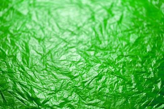 crumpled ufo green polyethilene film abstract background with selective focus.