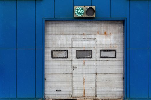 a white automatic upward sliding gate on blue garage with green lit traffic light.