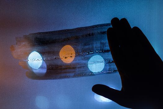 hand wiping night wet window glass - dark background and mockup.