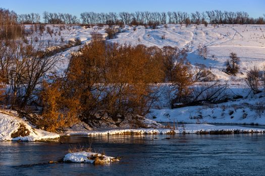 amateur winter riverside landscape with birch forest and slope.