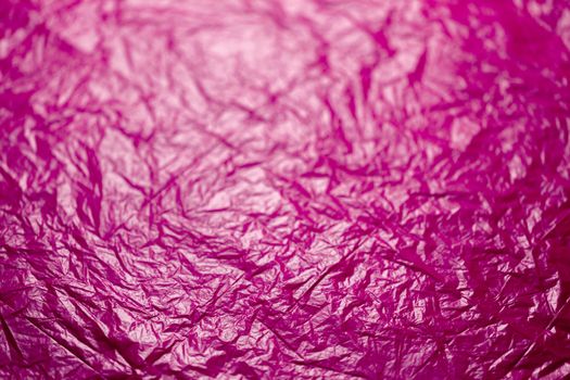 crumpled plastic pink polyethilene film abstract background with selective focus.
