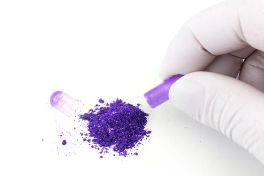 hand in medical glove opening proton purple color organic med capsule isolated on white background closeup.