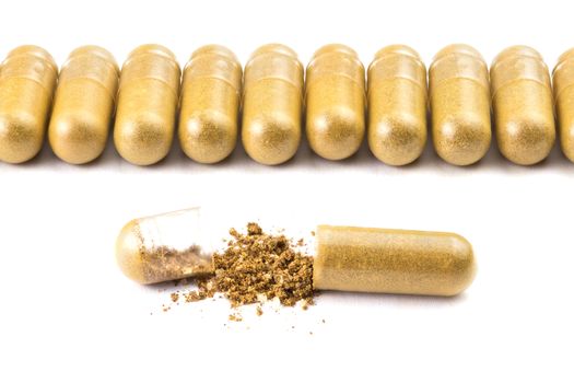 row of orange color organic capsules isolated on white background closeup with one opened.
