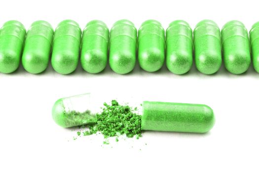 row of ufo green color organic capsules isolated on white background closeup with one opened.