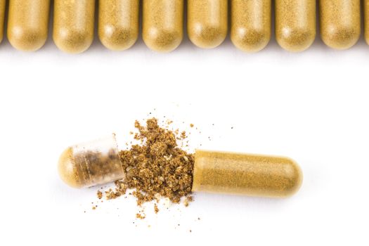row of orange color organic capsules isolated on white background closeup with one opened.