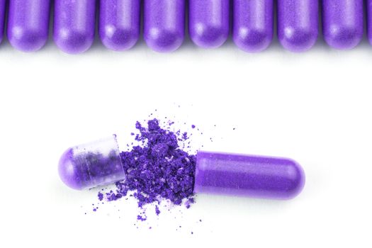 row of proton purple color organic capsules isolated on white background closeup with one opened.