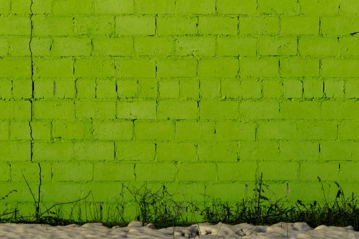 green plaster rough brick wall texture under direct sunlight with snow and dry gasss under