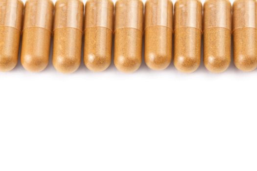 row of orange color organic capsules isolated on white background closeup with selective focus.