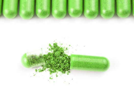 row of ufo green color organic capsules isolated on white background closeup with one opened.