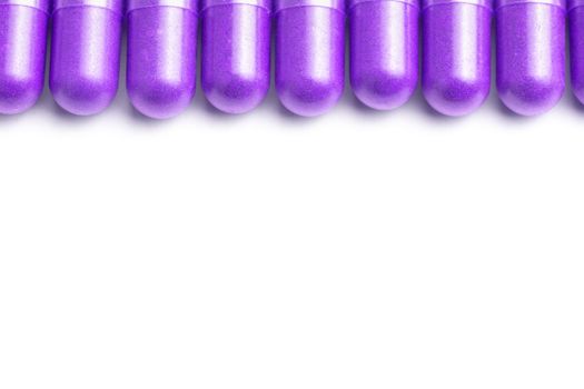 row of proton purple color organic capsules isolated on white background closeup with selective focus.