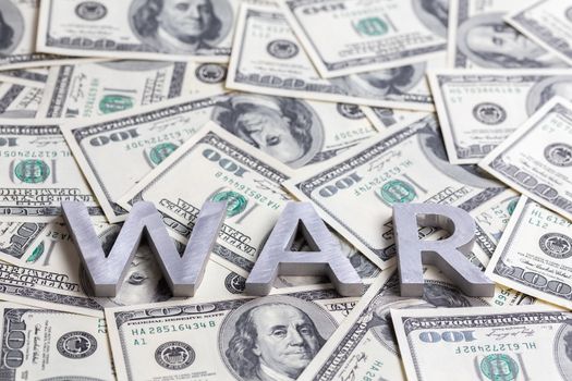 The word WAR laid with metal letters on the US dollar banknotes mosaic - close shot with selective focus