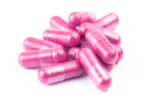 pile of pink organic capsules isolated on white background closeup with selective focus.