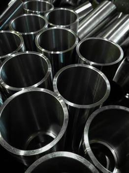 dark industrial background with cnc machined shiny steel pipes - selective focus and lens blur technique