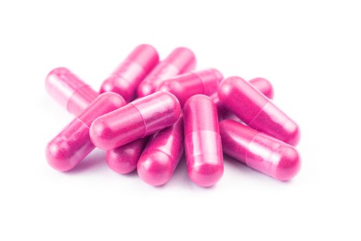 pile of pink organic capsules isolated on white background closeup with selective focus.