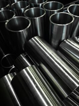 dark industrial background with cnc machined shiny steel pipes - selective focus and lens blur technique